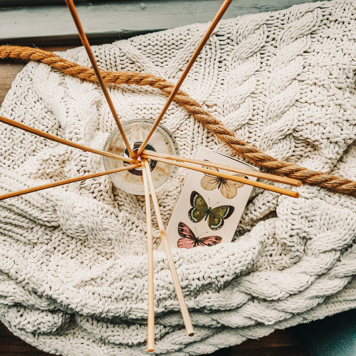 Reed diffuser sticks on a cream cable-knit throw, home air freshener