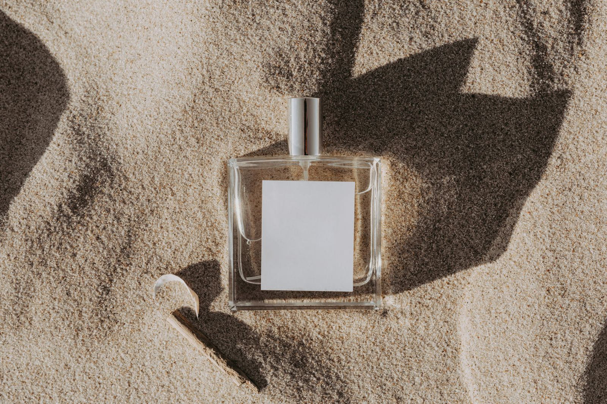 Clear fragrance bottle with blank label resting in sand, best sellers