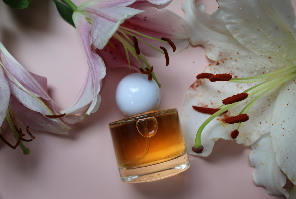 Amber fragrance bottle among pink lilies, for gift sets