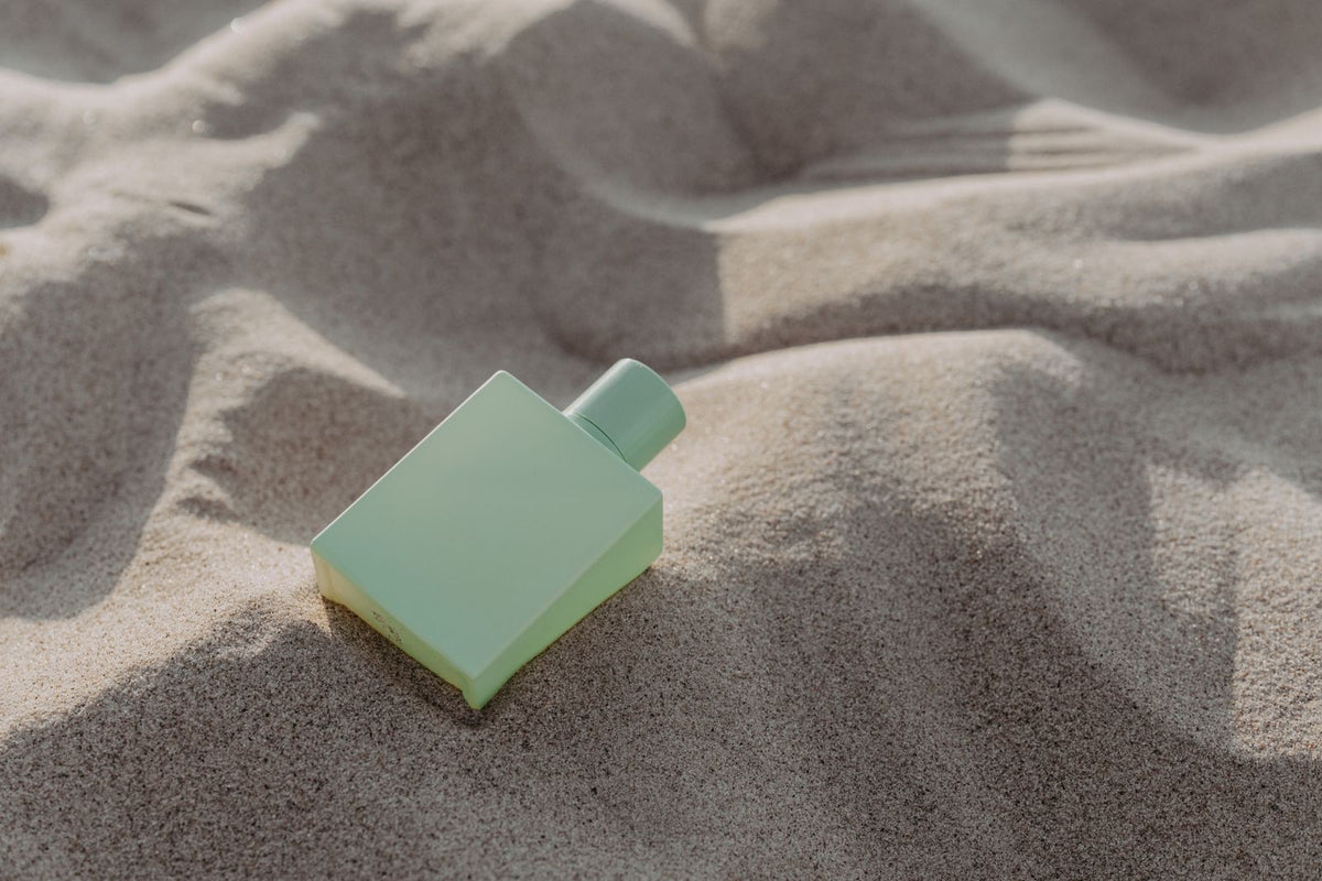 Mint green fragrance bottle lying in rippled sand, men's fragrances