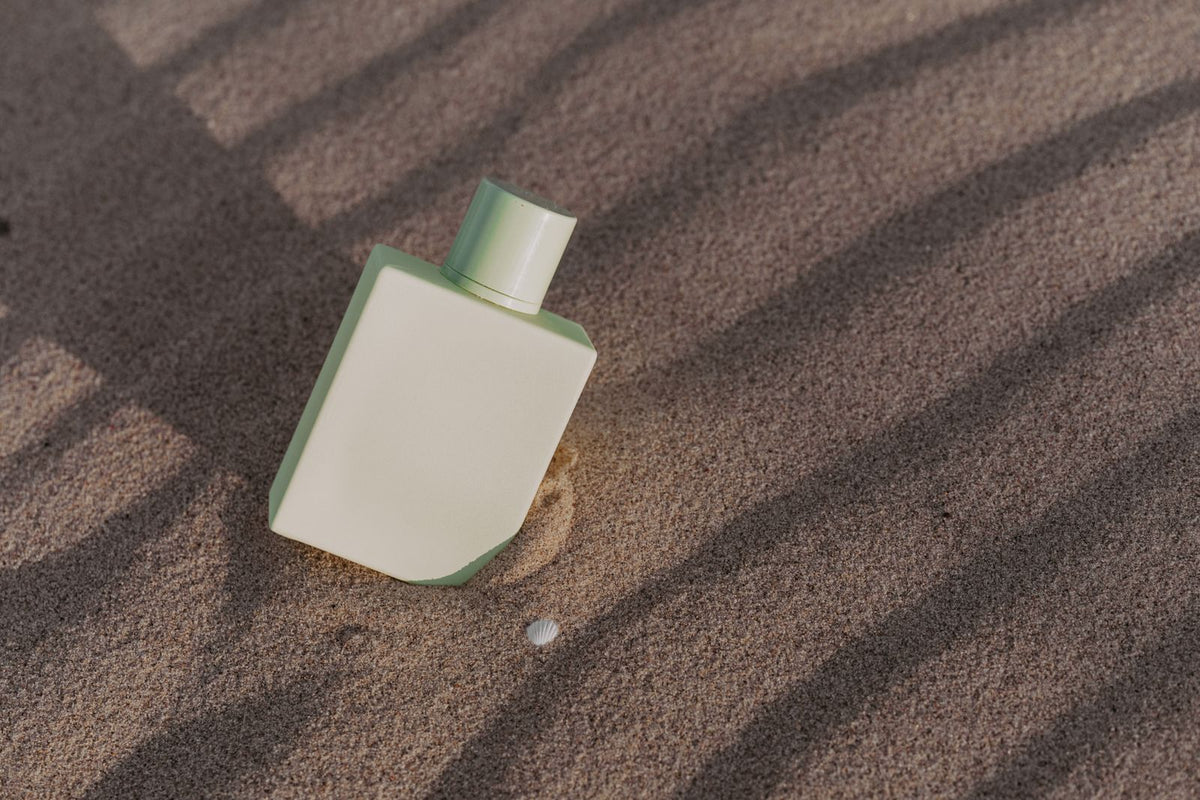 Soft cream fragrance bottle on sunlit sand, women's fragrances